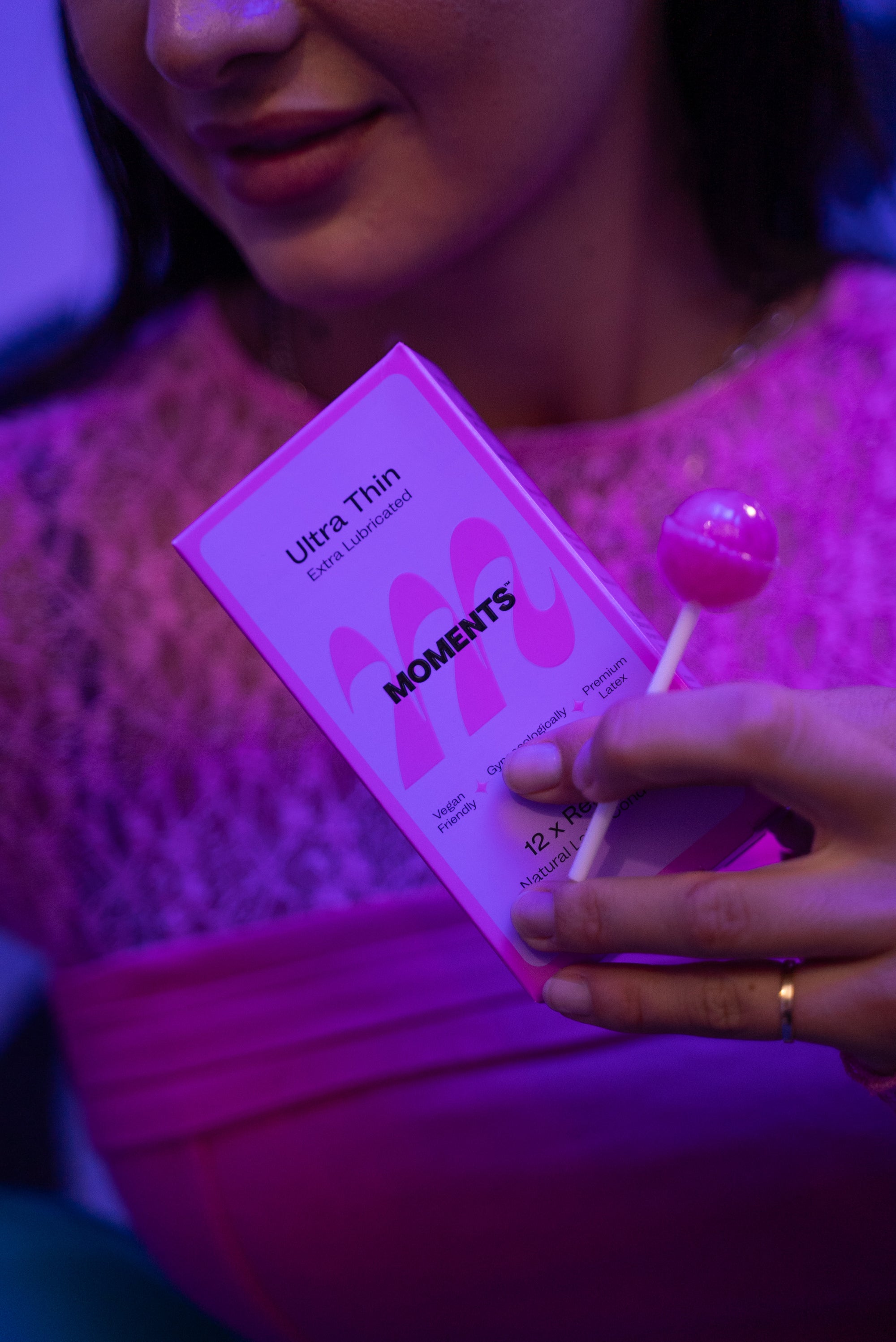 Moments Ultra Thin Regular condom product held by a woman with a subtle pink aesthetic