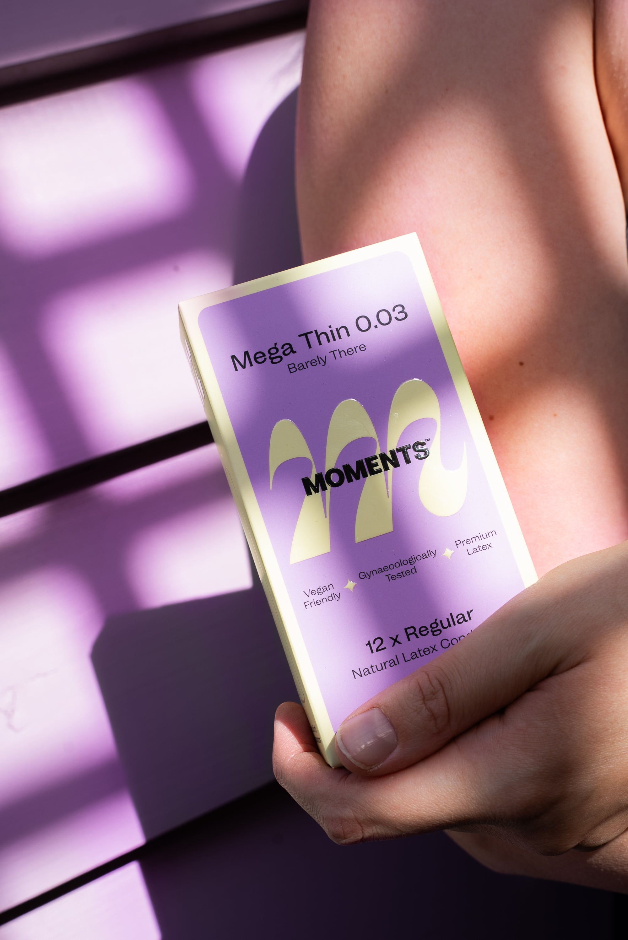 Person holding a Moments Mega Thin 0.03 condom package