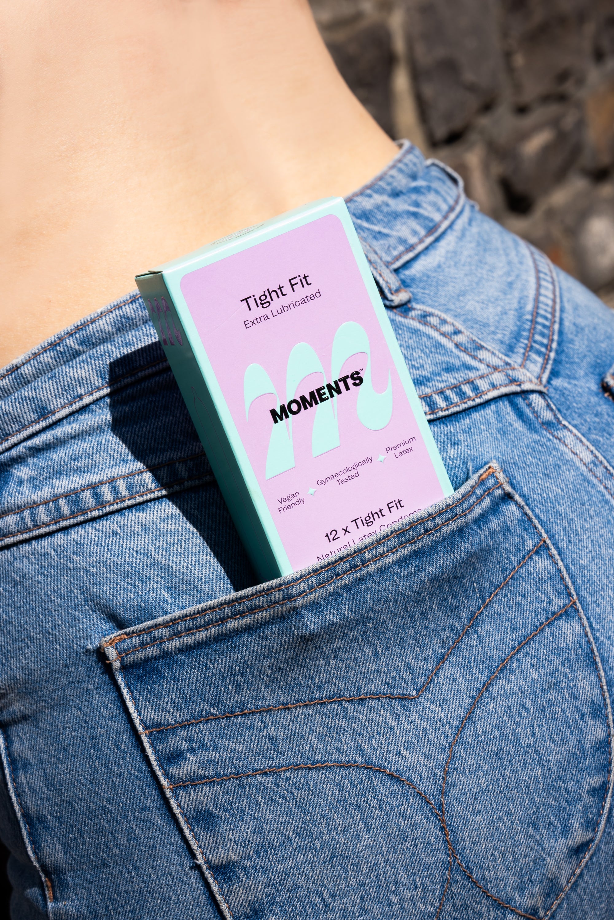 Box of Moments Tight Fit condoms in a woman's jeans back pocket
